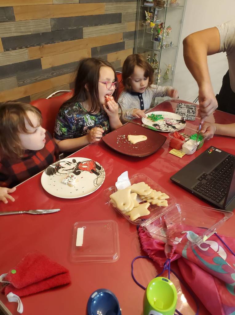 three children eating cookies while talking to santa on zoom call